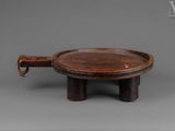 an old wooden tray with a handle on a stand