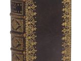 un vieux livre avec des bordures dorées et une couverture noire sur fond blanc