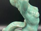 a green statue of a mermaid holding a vase