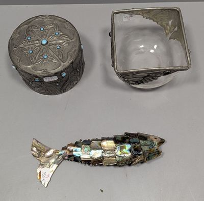 un poisson en argent posé à côté d'une boîte en argent et d'un récipient en argent
