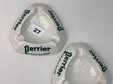 two white ashtrays with green lettering on them sitting on a white surface