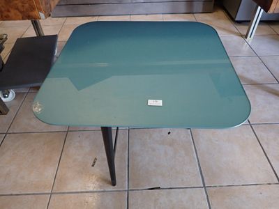 une table avec un plateau en verre posée sur un sol carrelé