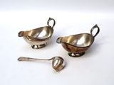 two silver plated dishes and spoons on a white surface