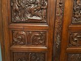 carvings on the doors of a large wooden cabinet in a room