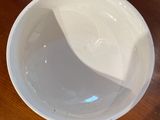 a white bowl sitting on a wooden table with a spoon in it