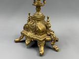 a gold candle holder on a stand on a gray surface