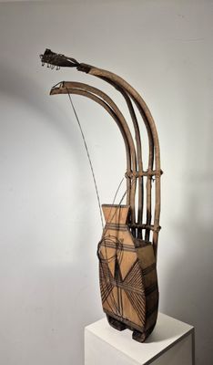 une sculpture en bois représentant un instrument de musique posée sur un socle blanc