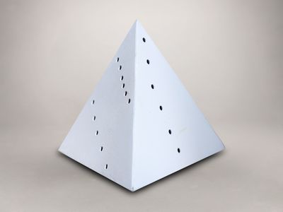 un gros plan d'une pyramide en papier blanc percée de trous