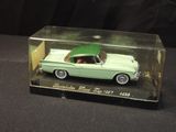 a green toy car in a clear box on a black surface