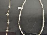 two necklaces and a pair of glasses are on display in a glass case