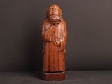 une vieille statue en bois représentant un moine barbu vêtu d'une robe