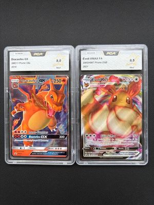 two pokemon cards in plastic cases on a black surface