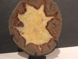 une assiette marron ornée d'une feuille, posée sur un socle