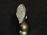 gros plan d'une bague en perles et diamants sur une surface noire