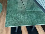 une table avec un plateau en marbre vert et des pieds en métal noir