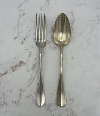 deux cuillères en argent et une fourchette posées sur une table en marbre