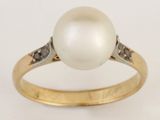 gros plan d'une bague en perles et diamants sur fond blanc