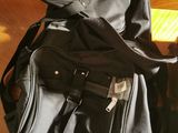 a black backpack sitting on top of a bed next to a black bag