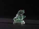 green glass figurine of a frog on a black background