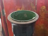 a black trash can with a green lid sitting on the floor