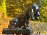 une statue représentant un chien assis sur un rocher