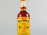 une vieille bouteille de whisky bourbon Taylor posée sur une surface blanche