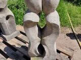 trois sculptures en pierre posées sur une palette près d'un arbre