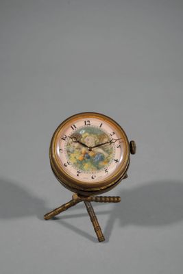 une petite horloge posée sur un trépied