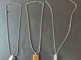 trois colliers en argent et en or posés sur une surface noire