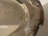 a silver plate on a table with a shadow on the wall
