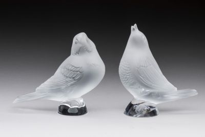 une paire d'oiseaux en verre blanc posés sur un socle noir