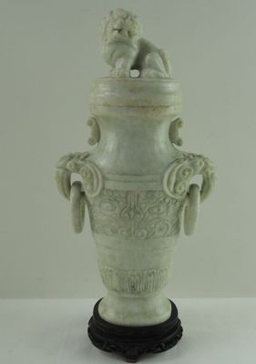 un vase blanc surmonté d'une statue