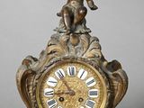 a statue of a boy holding a bell on top of a clock