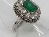 a close up of a ring with a green stone surrounded by white diamonds