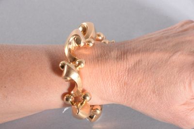 la main d'une femme à laquelle est attaché un bracelet en or