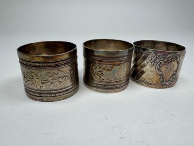 three silver cups with designs on them sitting on a white surface