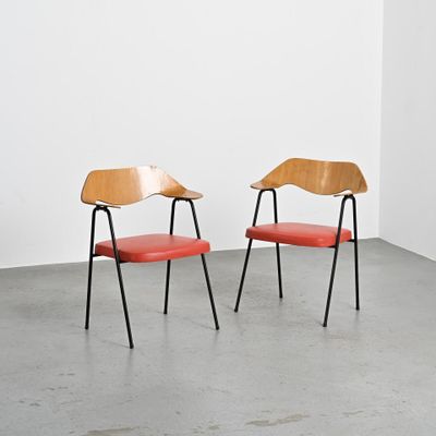 deux chaises en bois avec des assises en cuir rouge dans une pièce blanche