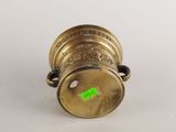 a close up of a brass vase with a green sticker on it
