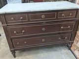 a marble top chest of drawers in the middle of a room