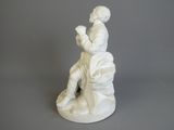 white statue of a man sitting on a rock with a bird in his hand