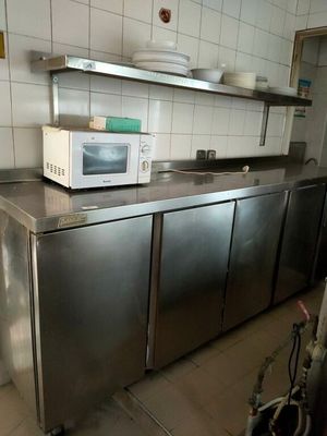un micro-ondes posé sur un plan de travail dans une cuisine équipée d'armoires en acier inoxydable