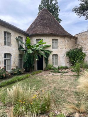 une photo d'un bâtiment en pierre avec un jardin devant