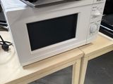 a microwave sitting on a table with a charger on top of it