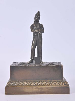 bronze figurine of a man holding a shovel on a base