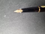 a black pen with a gold tip on a table