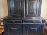 une vieille armoire noire à deux portes et un tiroir
