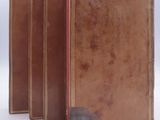 four brown leather books lined up in a row on a white surface