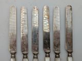 five silverware knives are lined up in a row on a table
