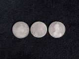three silver coins sitting on top of a black surface
