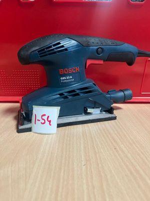 une ponceuse orbitale Bosch posée sur une table, à côté d'une boîte rouge
